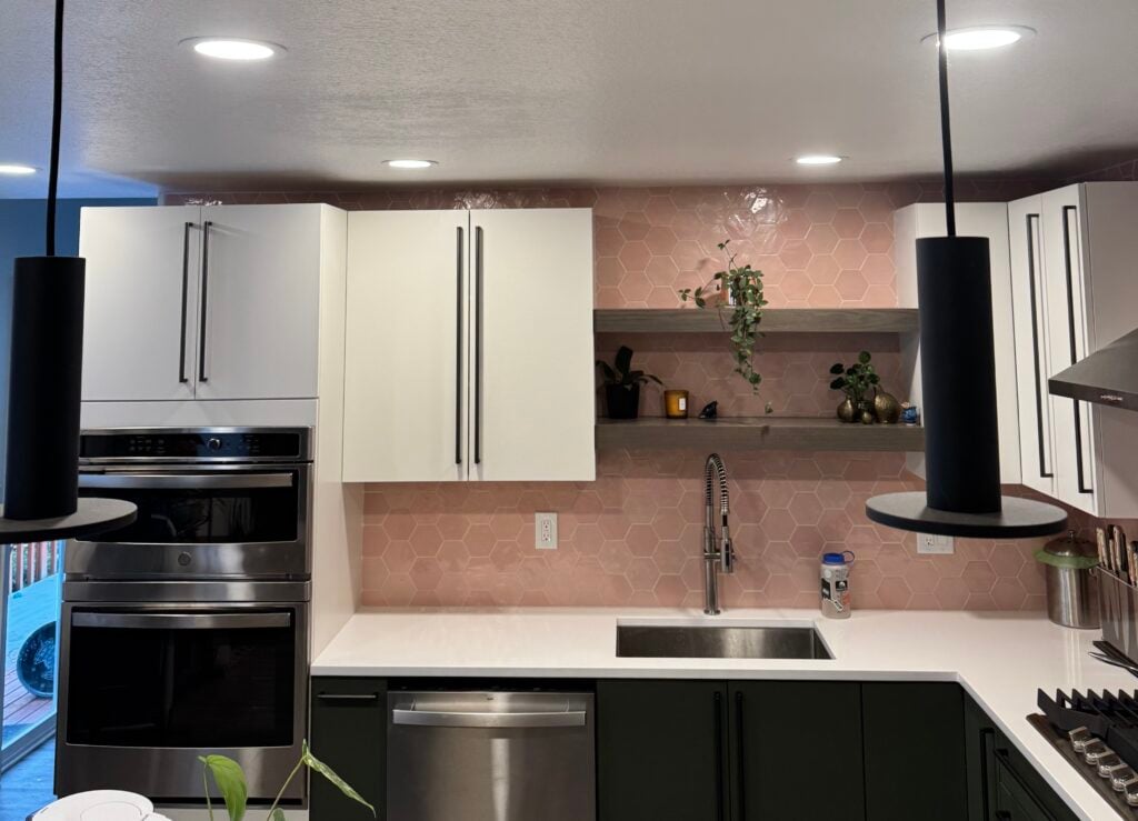 Green lower and white upper kitchen cabinets with pink hexagon tile backsplash